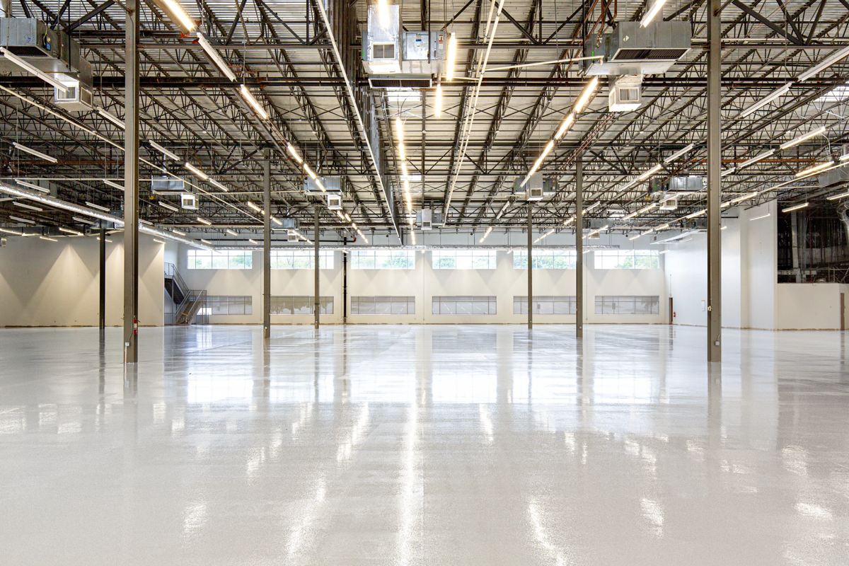 The bright, empty interior of a modern light-industrial unit with a polished concrete floor and daylight from clerestory windows.